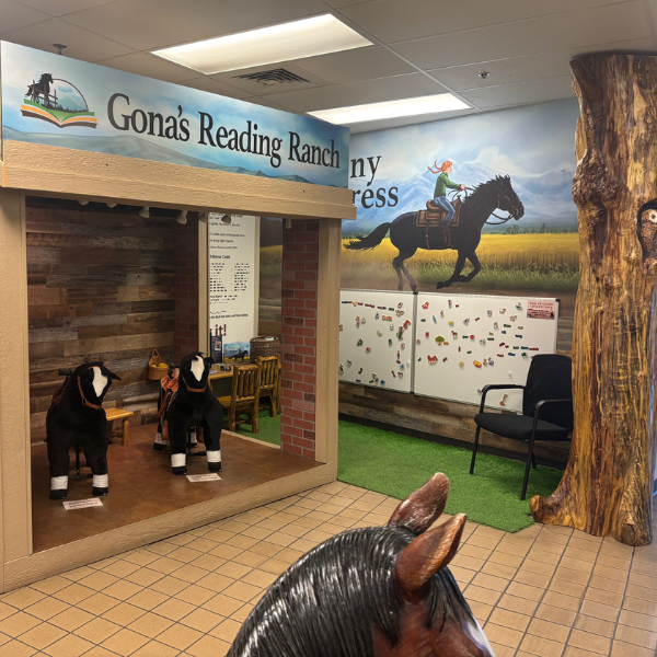 Exhibit with pretend play horses kids can sit on, tree, white board with words and symbols