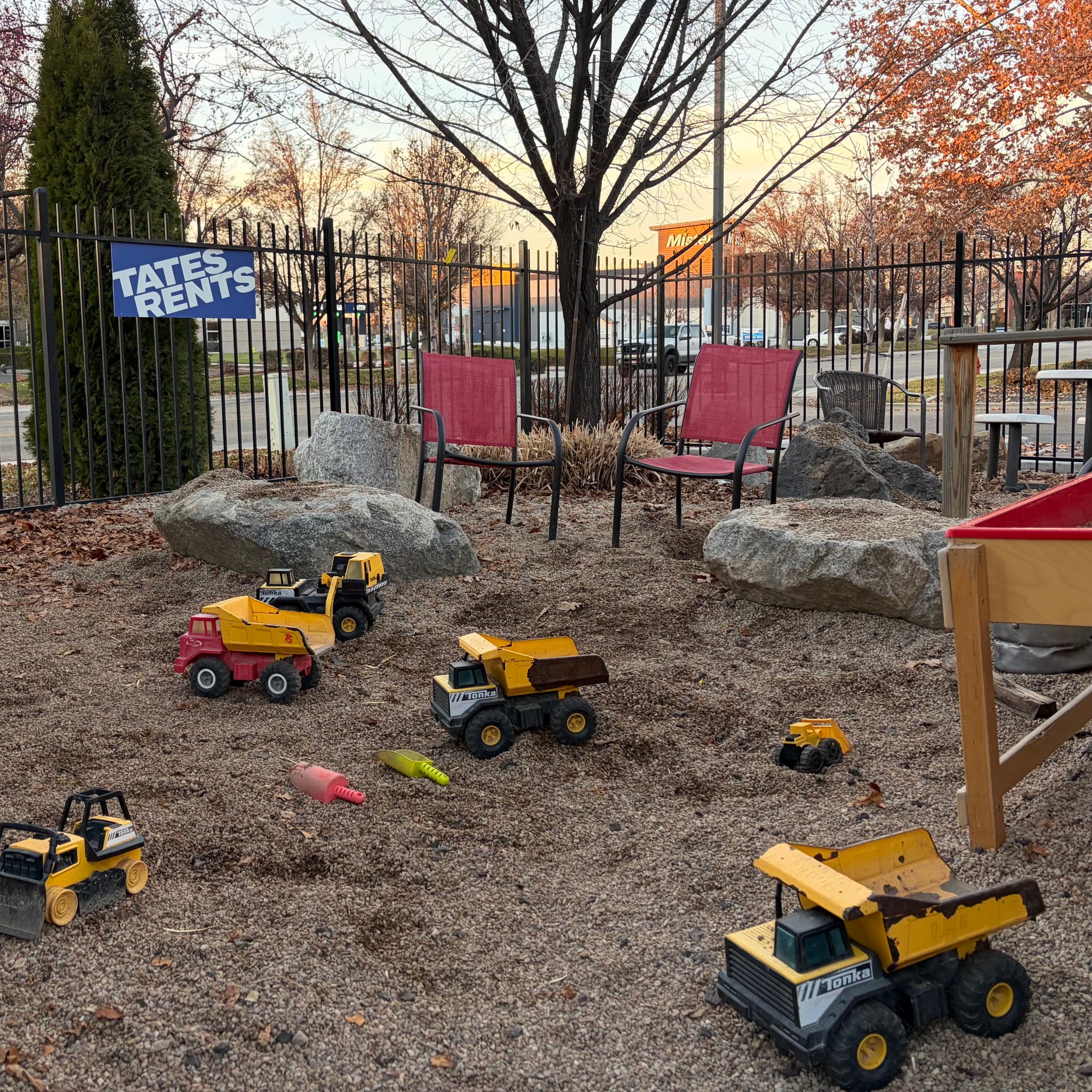 Gravel pit area with construction trucks, shovels, and other sand toys