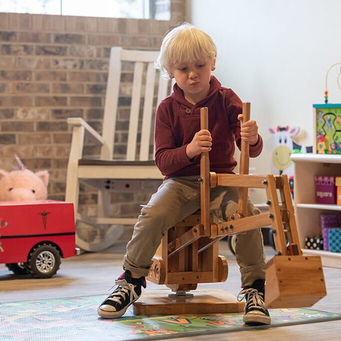 child sitting on wooden excavator playing
