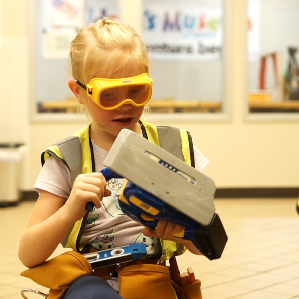 A girl at the Children's Museum of Idaho playing with pretend construction tools