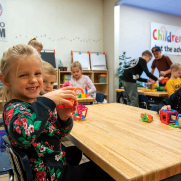 Two smiling girls playing at a desk at the Children's Museum of Idaho